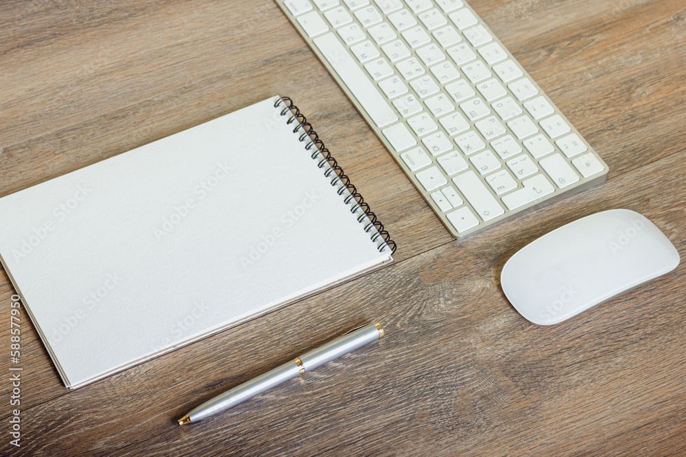 Notepad and pen with keyboard on wooden table Notepad and pen with keyboard on wooden table