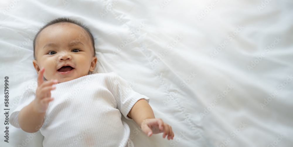 Close up portrait view of Young cute Asian baby crawling on bed in bedroom.The newborn baby or kid smiling at the right with joyfulness and happiness at home.baby health care concept,copy space. Close up portrait view of Young cute Asian baby crawling on bed in bedroom.The newborn baby or kid smiling at the right with joyfulness and happiness at home.baby health care concept,copy space.