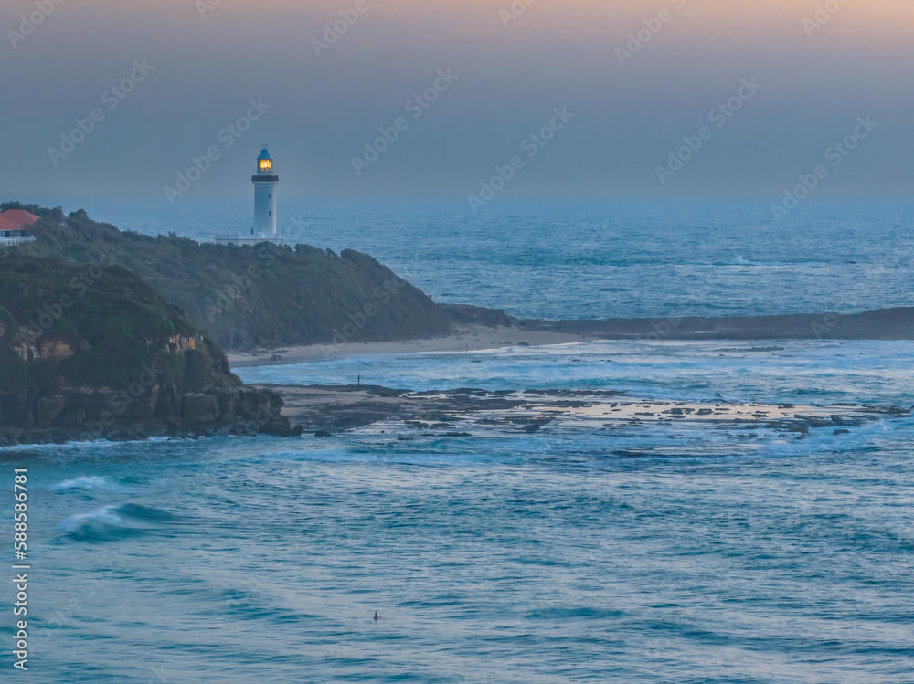 Aerial sunrise seascape with lighthouse, high tide and rock platform