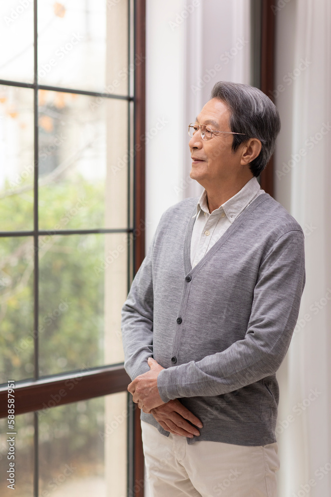 Senior Chinese man standing in front of window Senior Chinese man standing in front of window