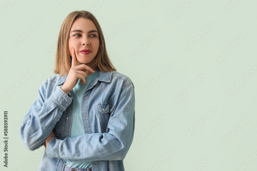 Thoughtful young woman in denim shirt on green background Thoughtful young woman in denim shirt on green background