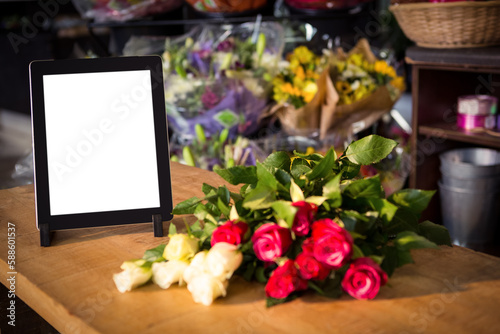 Digital tablet by fresh flowers on table