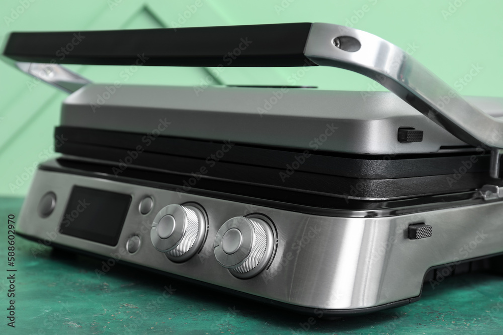 Modern electric grill with closed lid on green table Modern electric grill with closed lid on green table