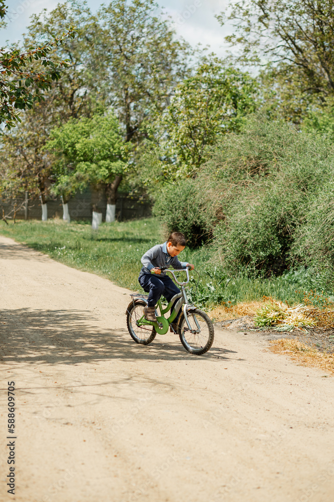 Happy child riding his bike outside his home. Young boy learning to ride his bicycle. Portrait little boy enjoy having fun riding exercise bike. Child first bike. Kid outdoors sport summer activities Happy child riding his bike outside his home. Young boy learning to ride his bicycle. Portrait little boy enjoy having fun riding exercise bike. Child first bike. Kid outdoors sport summer activities