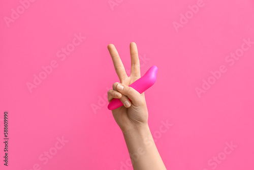Woman with vacuum vibrator showing victory gesture on pink background