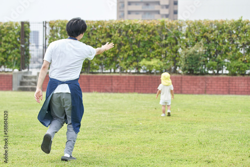 芝生で子供を追いかける男性の保育士