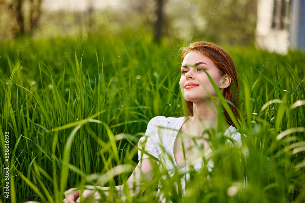 a young woman in a light summer dress enjoys nature sitting in the tall grass a young woman in a light summer dress enjoys nature sitting in the tall grass