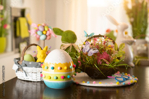 Easter theme. Easter decorations. Easter eggs in basket and easter bunny. Bouquet of spring flowers. Shining wooden brown table.