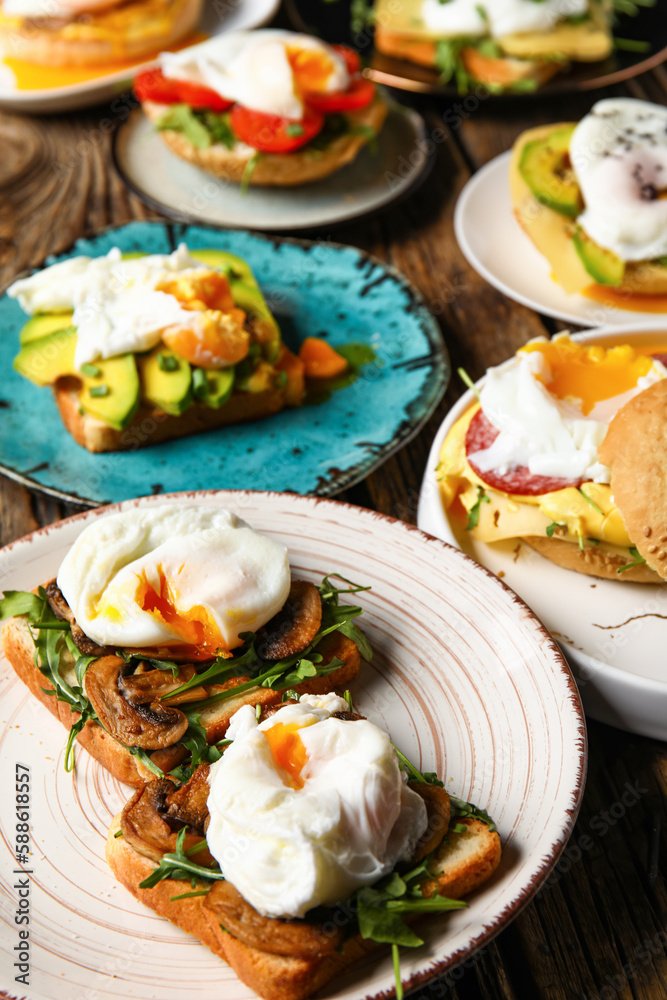 Plates with tasty eggs Benedict on wooden background