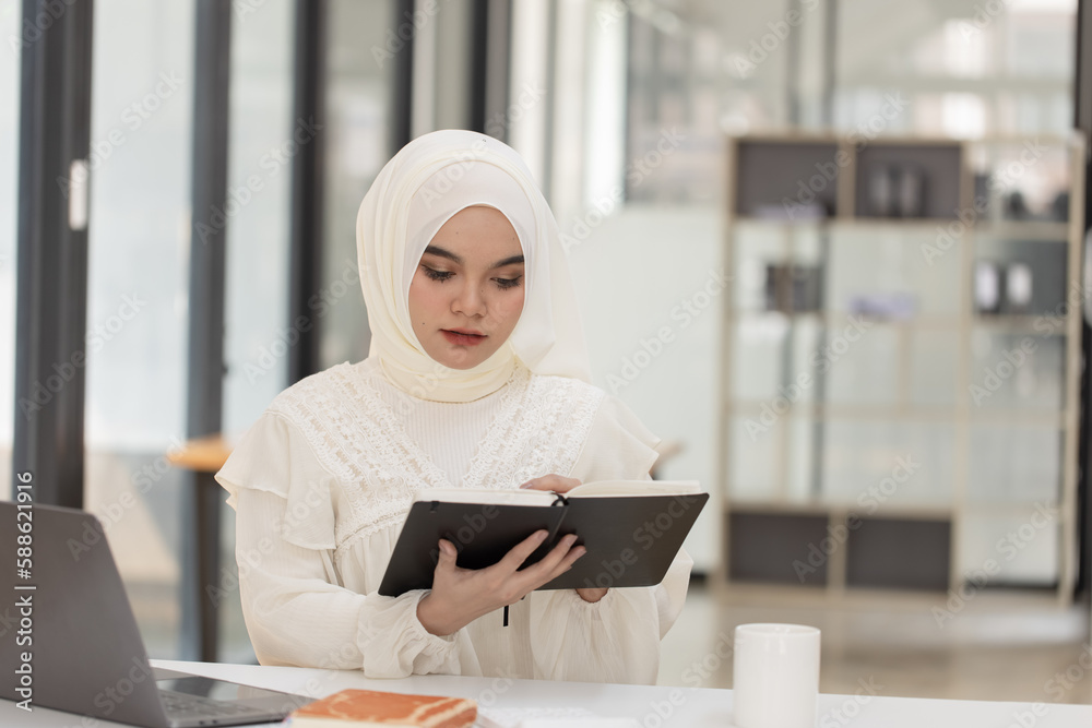 Happy Asian Muslim Woman working at desk in office, Businesswoman and education online concept. Happy Asian Muslim Woman working at desk in office, Businesswoman and education online concept.