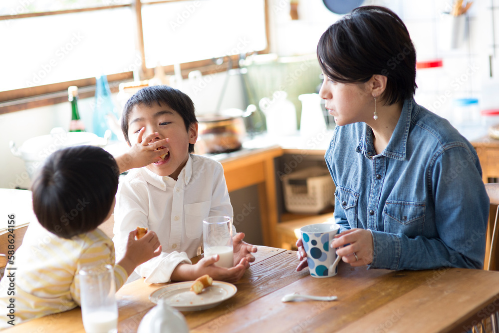 キッチンのテーブルでおやつを食べる兄弟と母親 キッチンのテーブルでおやつを食べる兄弟と母親