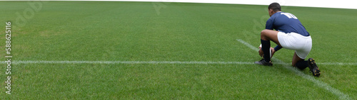 Male rugby player placing the ball on sports field