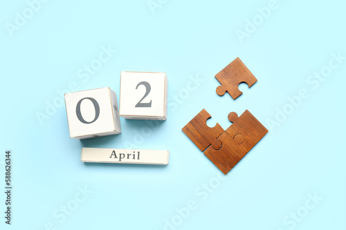 Date of World Autism Awareness Day and puzzle pieces on blue background