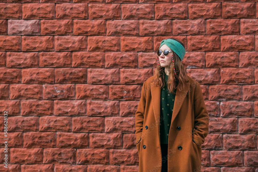 Portrait of a young 30+ hipster woman in sunglasses and stylish clothes in the city against a brick wall. Modern lifestyle. Portrait of a young 30+ hipster woman in sunglasses and stylish clothes in the city against a brick wall. Modern lifestyle.