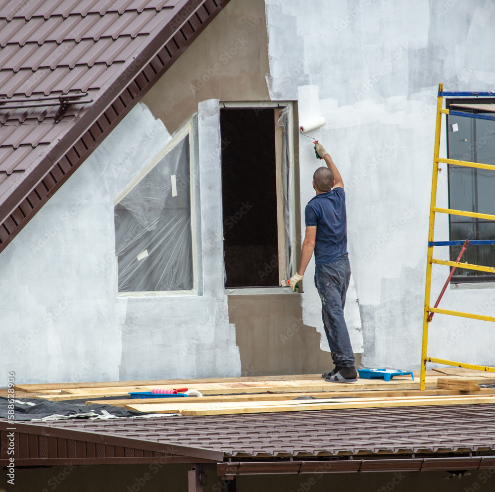 Workers are priming outside the walls of the house. Workers are priming outside the walls of the house.