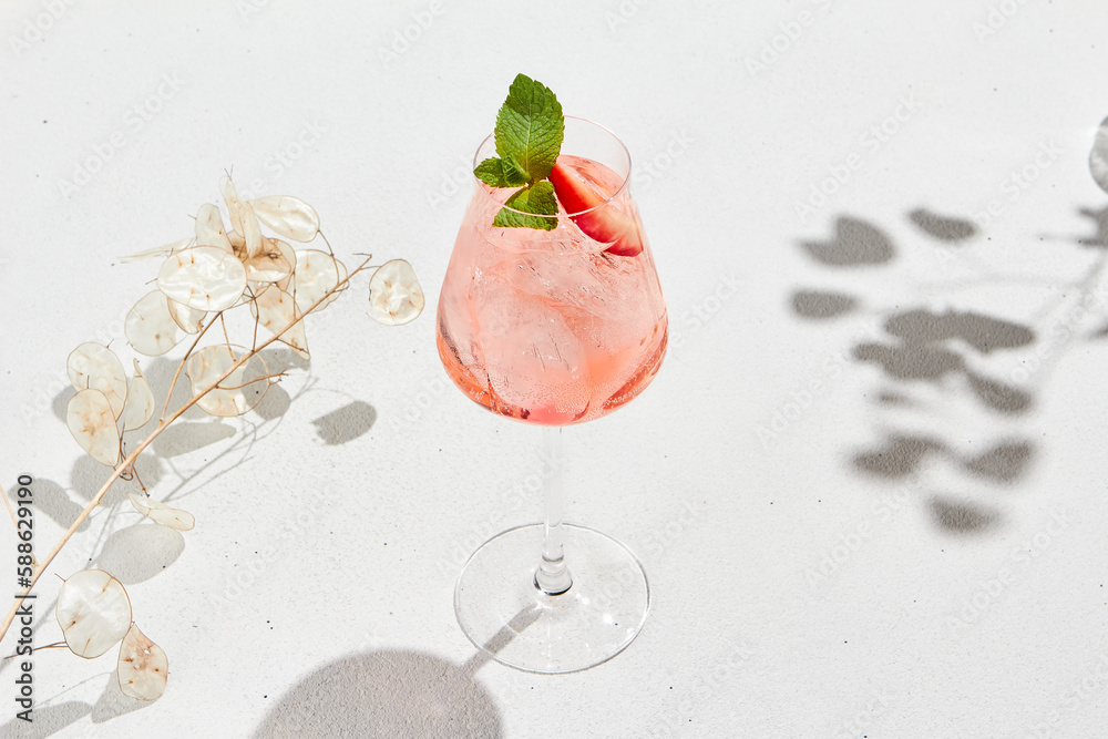 Strawberry alcoholic cocktail on white background with shadows. Summer drink strawberry spritz with empty place. Strawberry mocktail in minimal style. Pink cocktail in summer menu on light background. - obrazy, fototapety, plakaty 