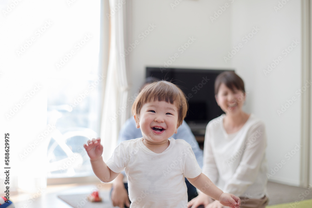 リビングで歩く赤ちゃんとそれを見守る父親と母親 リビングで歩く赤ちゃんとそれを見守る父親と母親