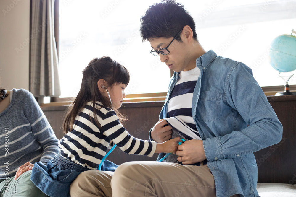父親のお腹に聴診器を当てる女の子 父親のお腹に聴診器を当てる女の子