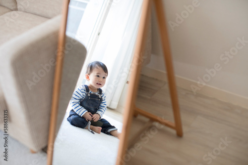 リビングルームで遊ぶ赤ちゃんが鏡に写った姿 photo