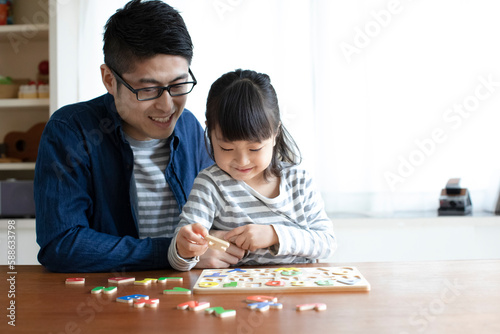 アルファベットのパズルをする女の子とそれを手伝う父親 photo