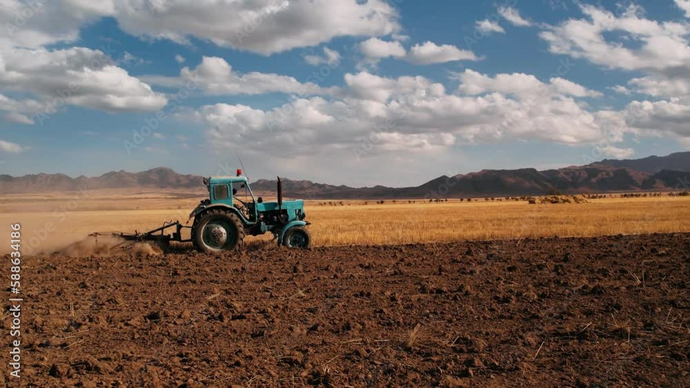 Aerial view tractor plowing field for sowing. Farm tractor with rotary harrow plow preparing land for sowing. Food industry concept. Agriculture. High quality 4k footage