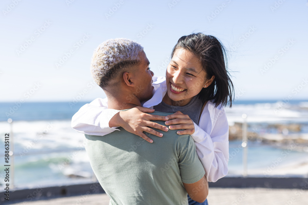 Happy diverse couple spending time together, embracing on promenade by the sea Happy diverse couple spending time together, embracing on promenade by the sea