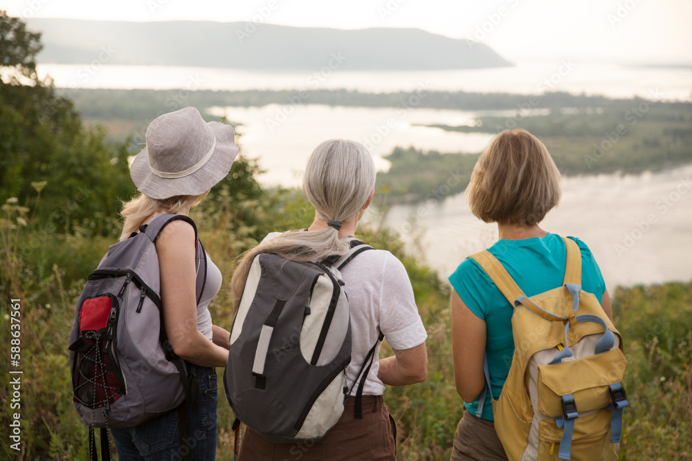 multi generation a group of women friends with backpacks standing on a mountain and spending time together. travel tourism concept. Outdoor activities on weekends. multi generation a group of women friends with backpacks standing on a mountain and spending time together. travel tourism concept. Outdoor activities on weekends.