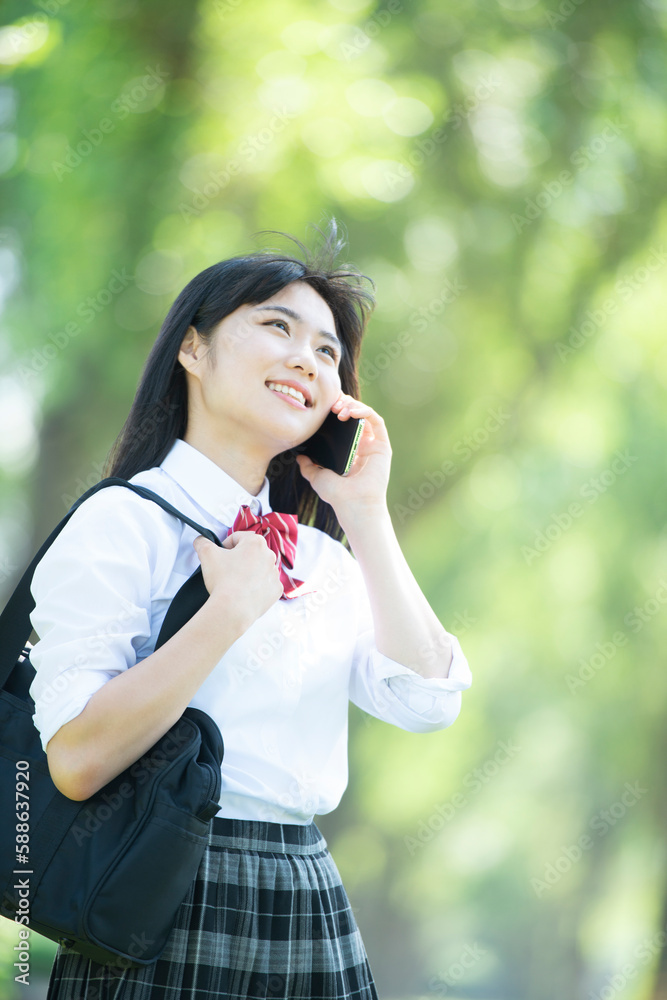 スマートフォンで電話をする女子学生 スマートフォンで電話をする女子学生
