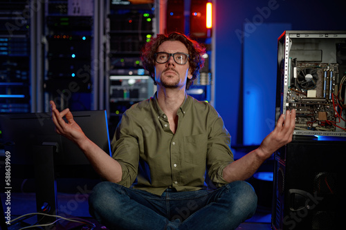 Pensive technician meditating in server room at modern data center