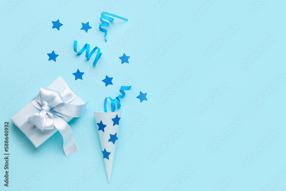 Party cone with serpentine, stars and gift on blue background