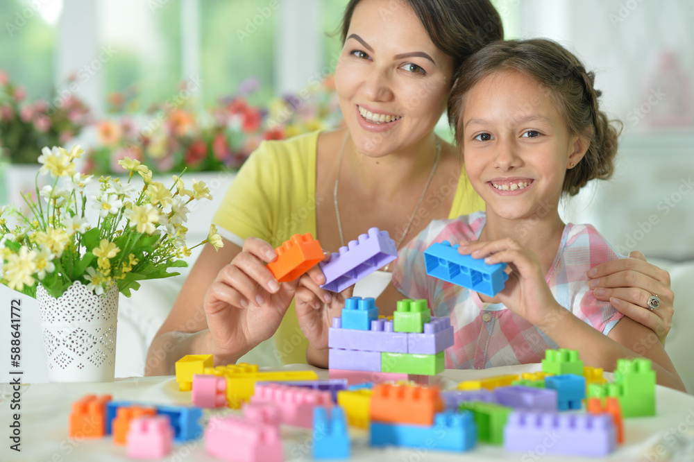 little daughter and mother playing with colorful plastic blocks at home little daughter and mother playing with colorful plastic blocks at home