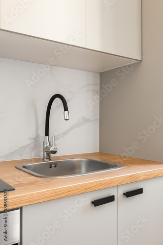 Piece of kitchen in gray solid colors with comfortable wall cabinets and modern fixtures in a new apartment. The concept of repair after the delivery of a new building. Copyspace