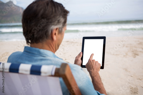 Man using digital tablet at beach