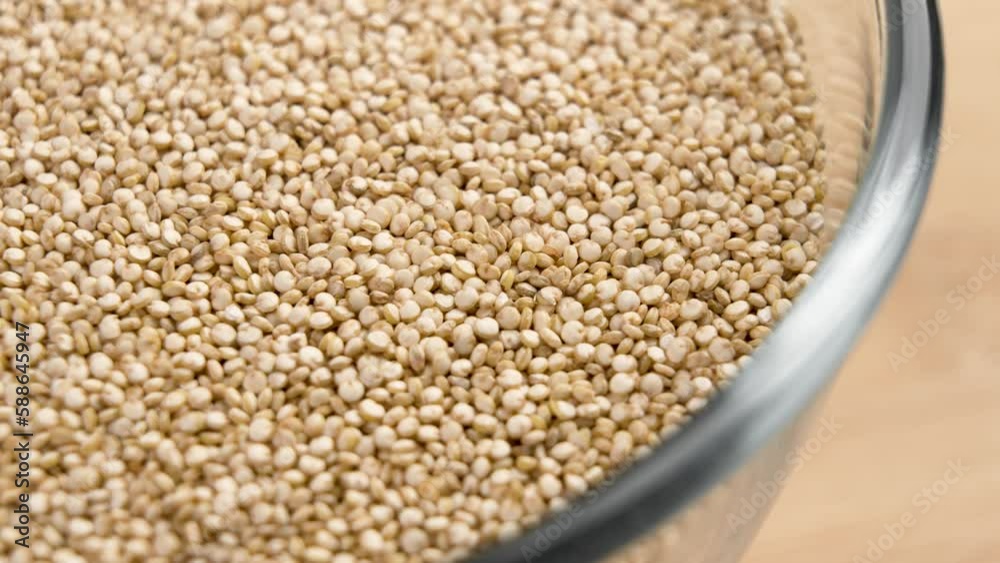 Full glass bowl of white quinoa seeds close up. Rotation. Superfood gluten free grains Full glass bowl of white quinoa seeds close up. Rotation. Superfood gluten free grains