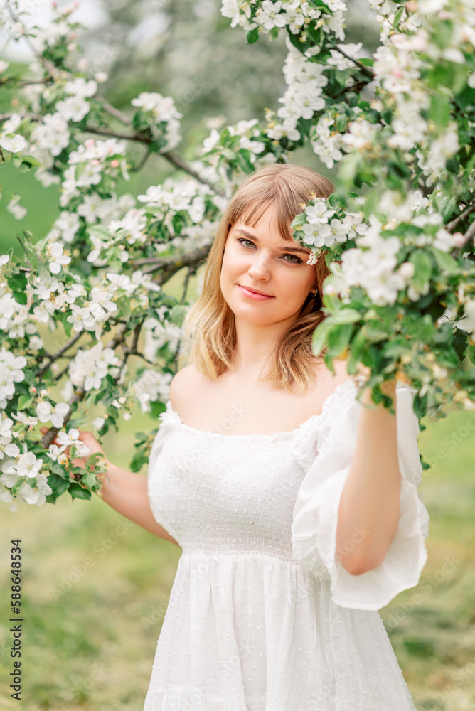 Portrait of pretty blong girl posing against the spring flowers