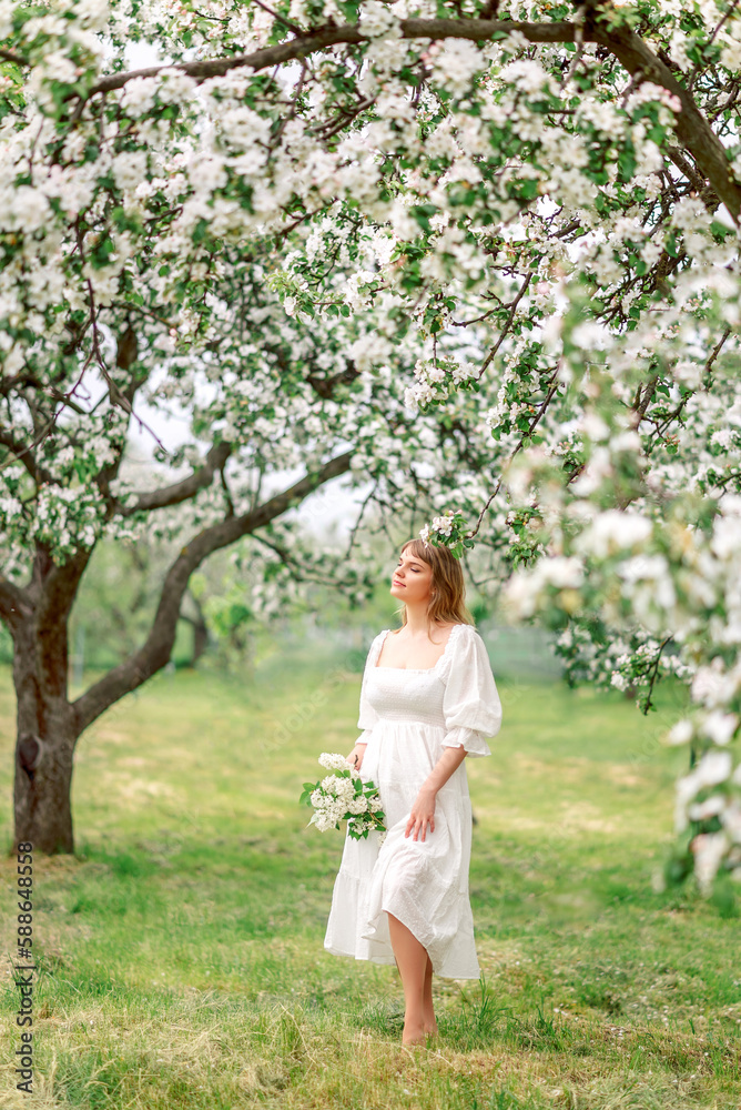 girl in a white dress in a spring garden with a bouquet of flowers.