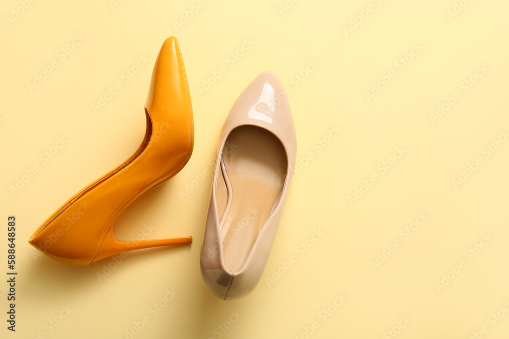 Stylish high heeled shoes on yellow background