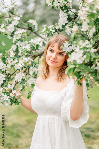 Portrait of pretty blong girl posing against the spring flowers