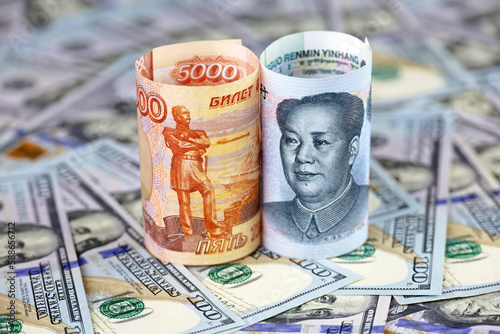 Chinese yuan banknote and russian ruble rolled up on US dollars background. Concept of strategic partnership between China and Russia, economic, tourism and investment