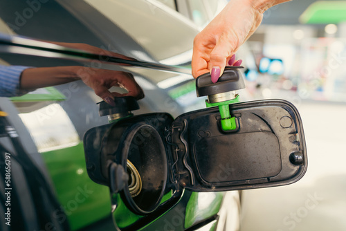 close-up image of a woman's hand opening the fuel tank of a car