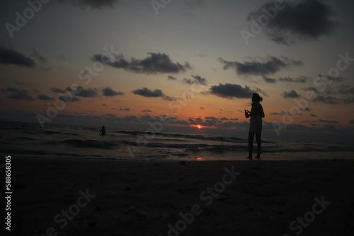 People walk on tropical beach at sunset, Koh Chang, Thailand.