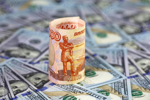 Russian rubles rolled up on background of US dollars. Concept of exchange rate, sanctions