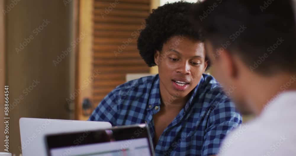 Two diverse male friends in kitchen with laptop and talking Two diverse male friends in kitchen with laptop and talking