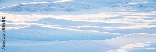 Snow texture. Wind sculpted patterns on snow surface. Wind in the tundra and in the mountains on the surface of the snow sculpts patterns and ridges. Arctic  Polar region. Winter panoramic background.