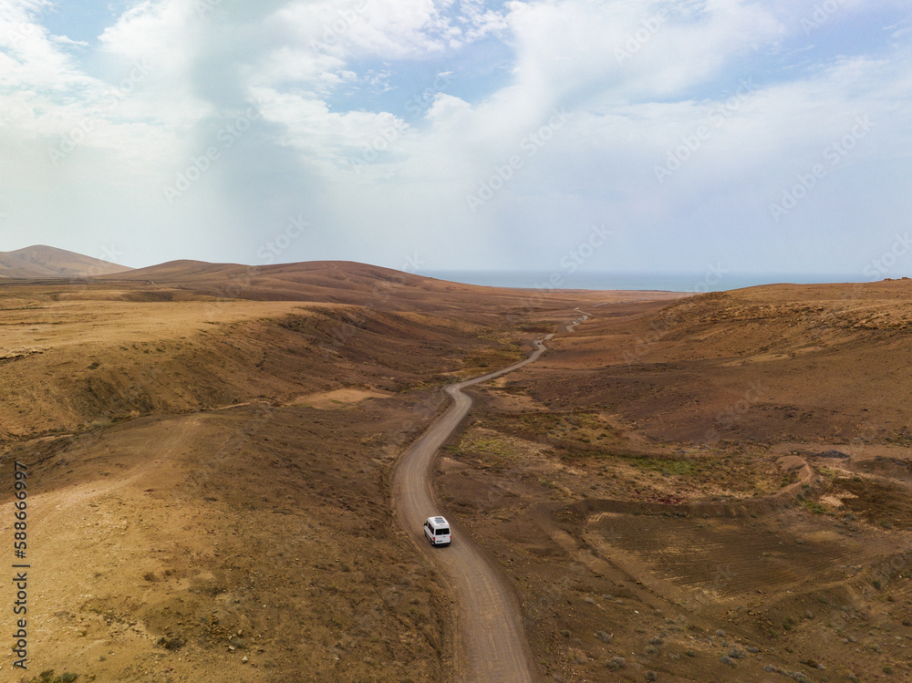 View from above, stunning aerial view of a van that travels on a deserted road in Fuerteventura, Canary Islands.