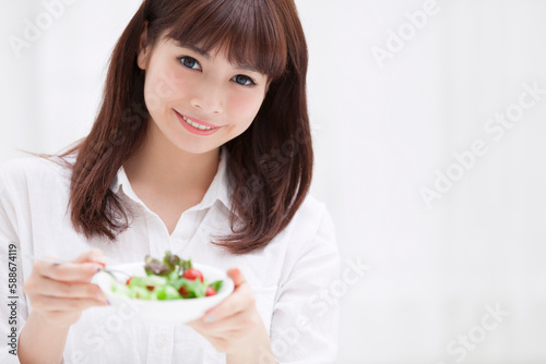 サラダの器を持って微笑む女性