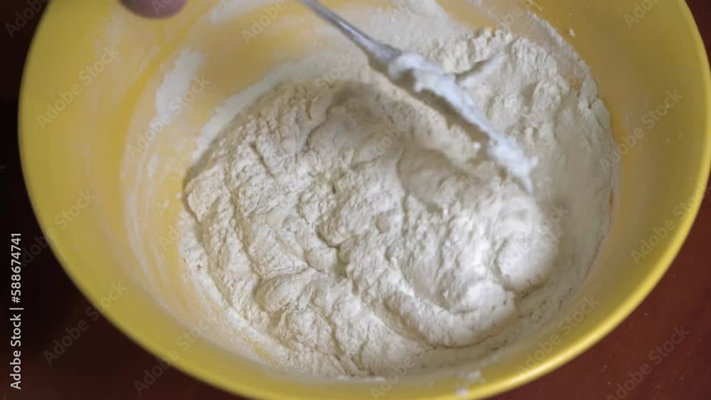 A woman's hand is kneading dough with a silicone spatula. A woman's hand is kneading dough with a silicone spatula.
