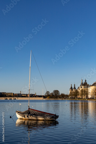 Copenhagen, Denmark An anchored saliboat with tarp on  the Peblinge Lake and residential buildings photo