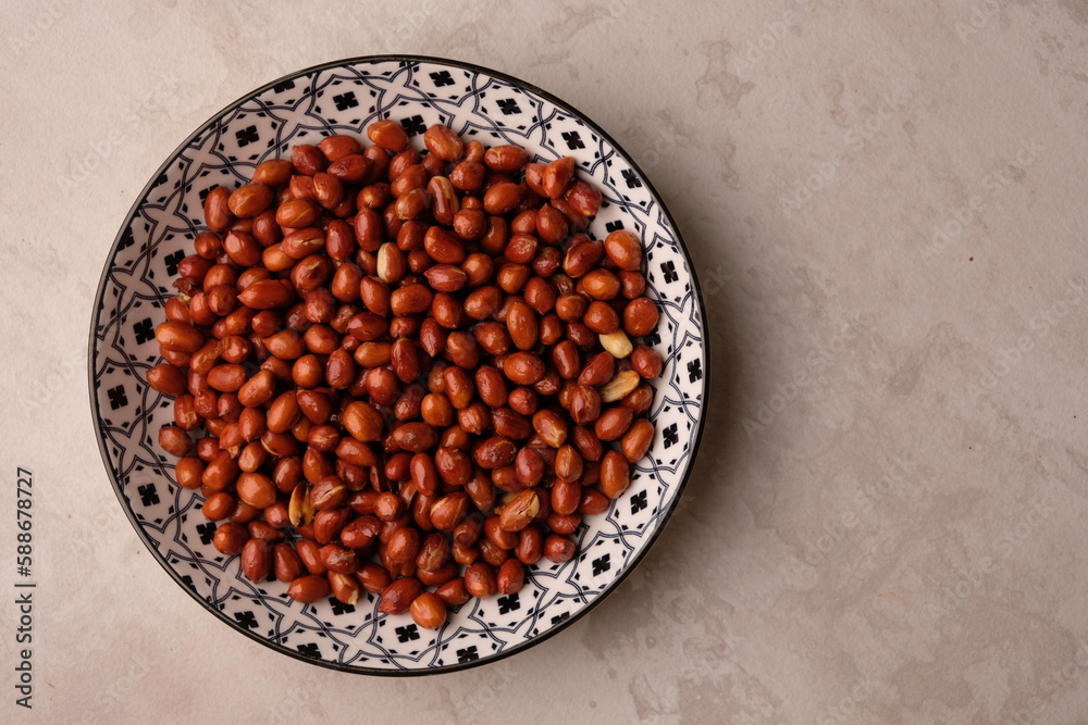 fried peanuts on a ceramic plate. Peanut (Arachis hypogaea L.) is a plant belonging to the Leguminosae tribe. kacang goreng. fried peanuts on a ceramic plate. Peanut (Arachis hypogaea L.) is a plant belonging to the Leguminosae tribe. kacang goreng.