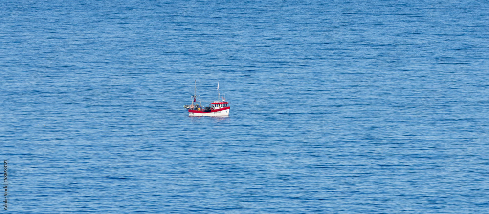 red and white fishing boat in the blue sea